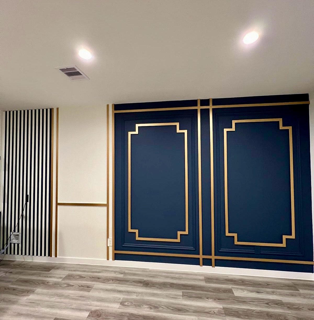 Navy blue dining accent wall with gold geometric molding and striped side panel.