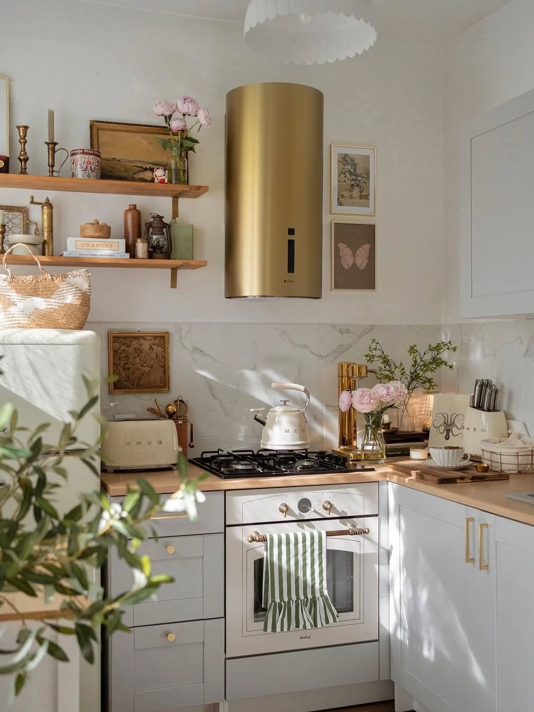 Kitchen featuring gold cylinder range hood and antique wall art