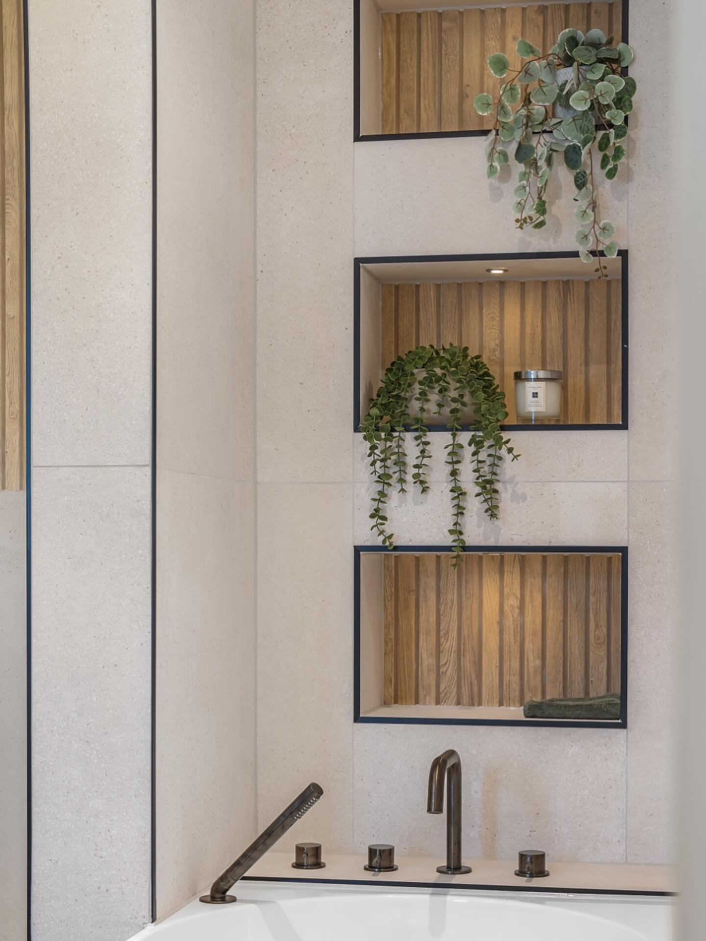 Bathroom wall decor featuring recessed niches with wood slats and LED lighting above bathtub