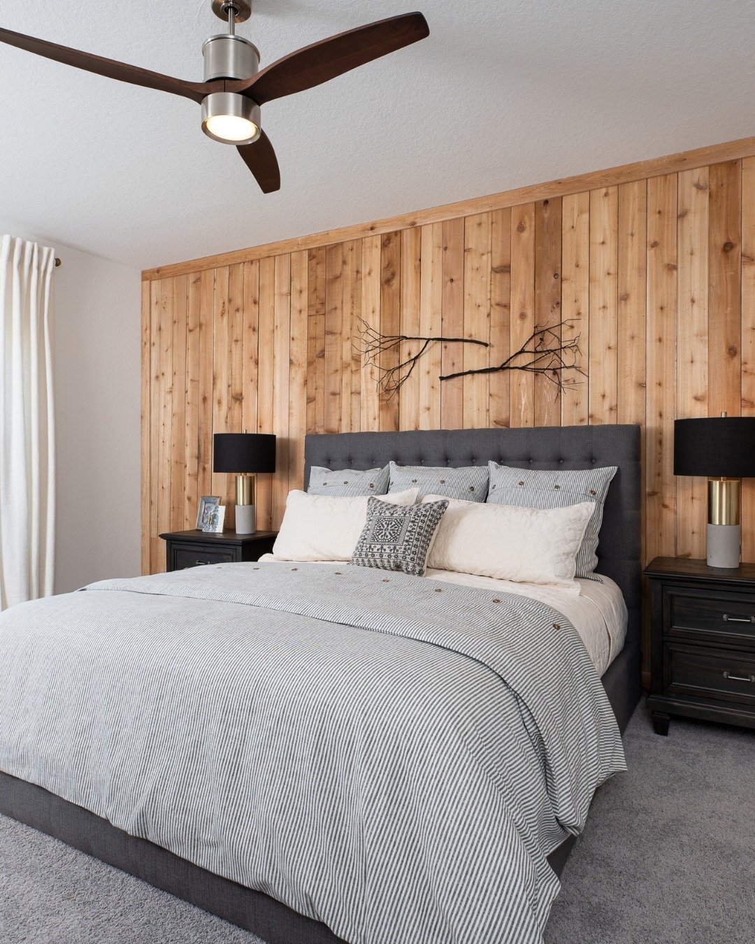 Bedroom featuring a natural wood vertical plank accent wall with a dark gray tufted headboard.
