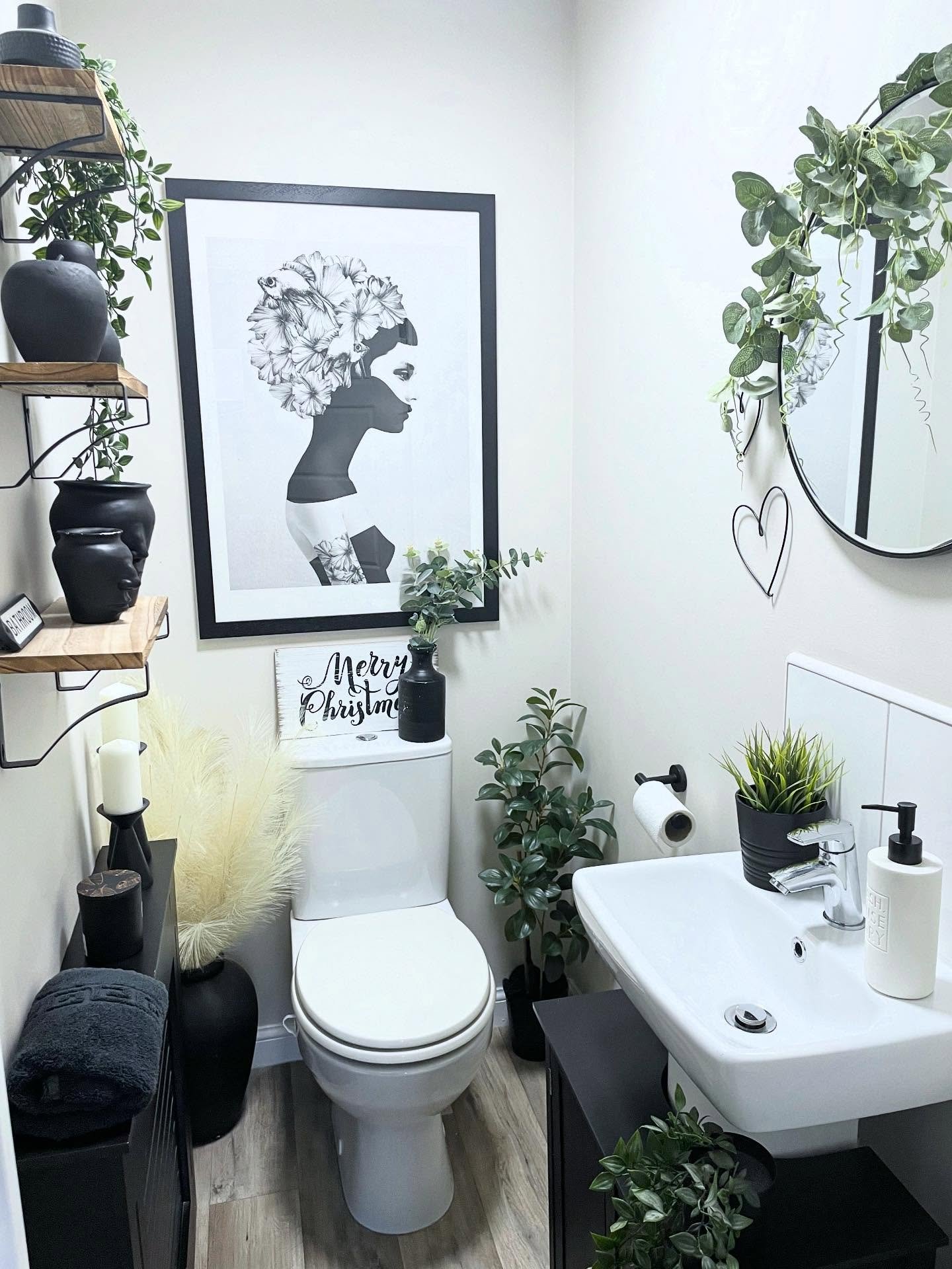 Bathroom wall decor featuring black and white art print with trailing plants and shelves