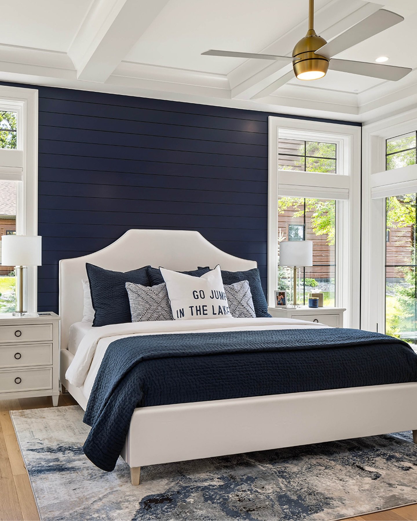 Navy blue horizontal shiplap accent wall with white upholstered bed and coastal decor