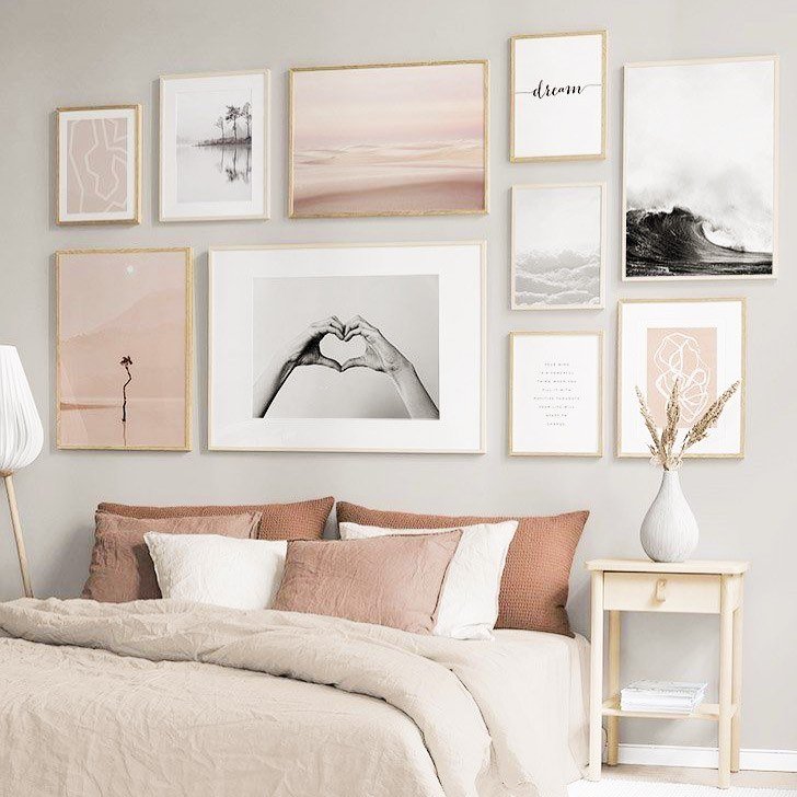 Bedroom wall decorated with a collection of framed art prints in blush pink and white tones