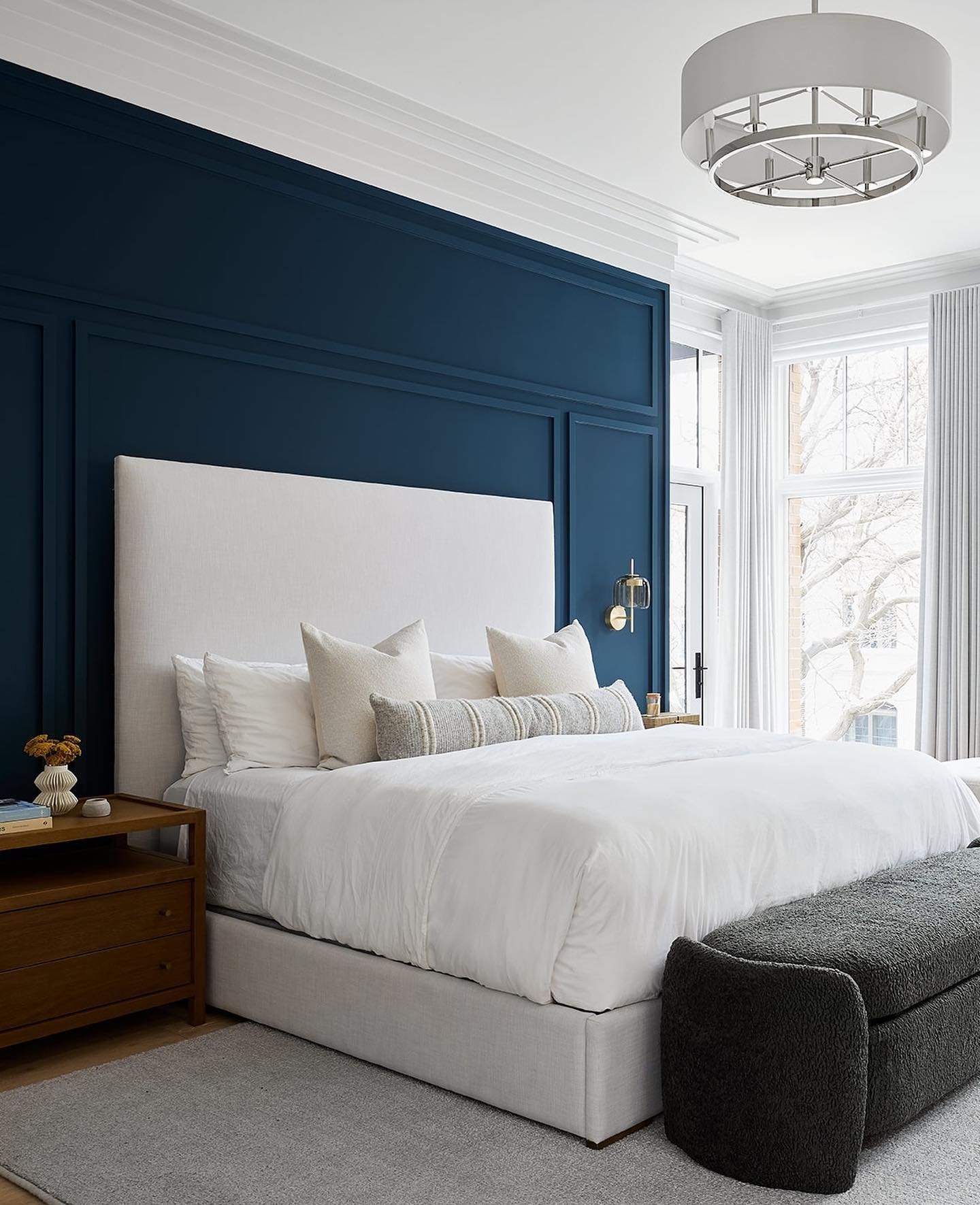 Navy blue large-scale paneled accent wall behind white upholstered headboard