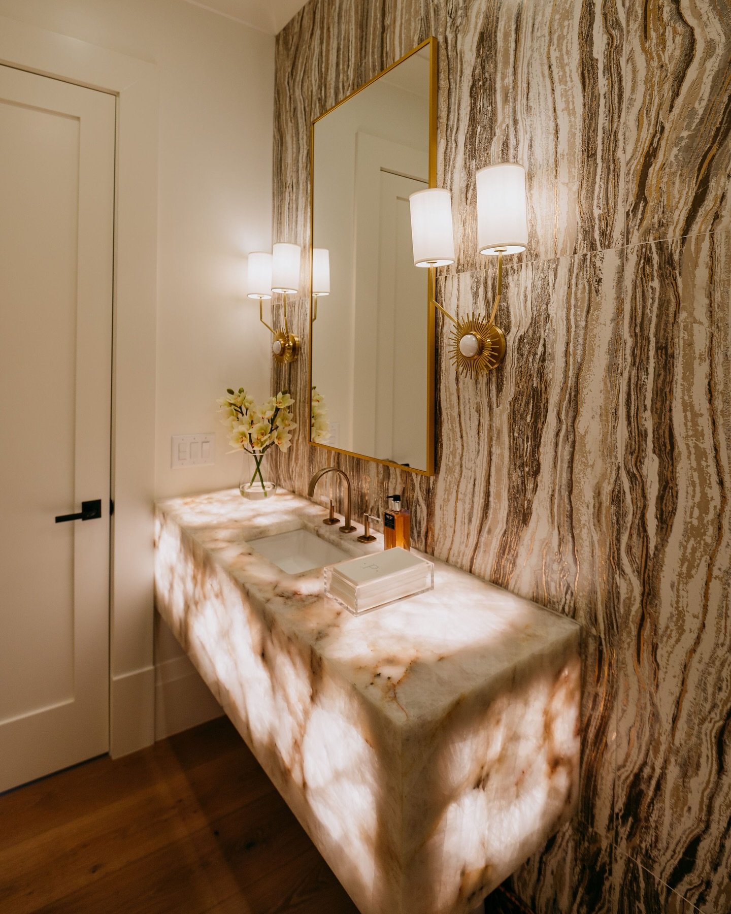 Powder room featuring agate-patterned wallpaper and a glowing onyx floating vanity.