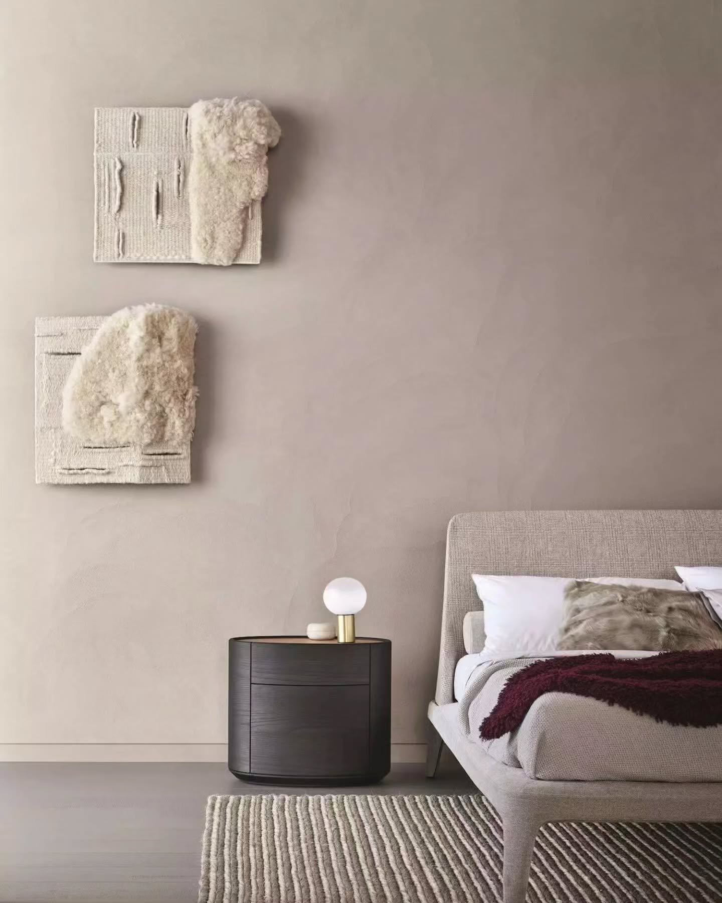 Beige bedroom accent wall featuring textured wool wall art and a round nightstand