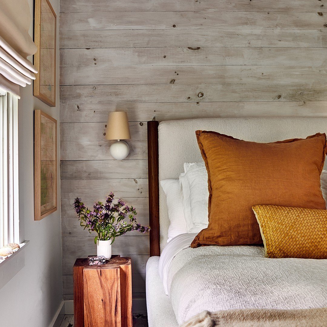 Vertical dark wood planks of varying lengths mounted on a white wall creating a dripping effect.