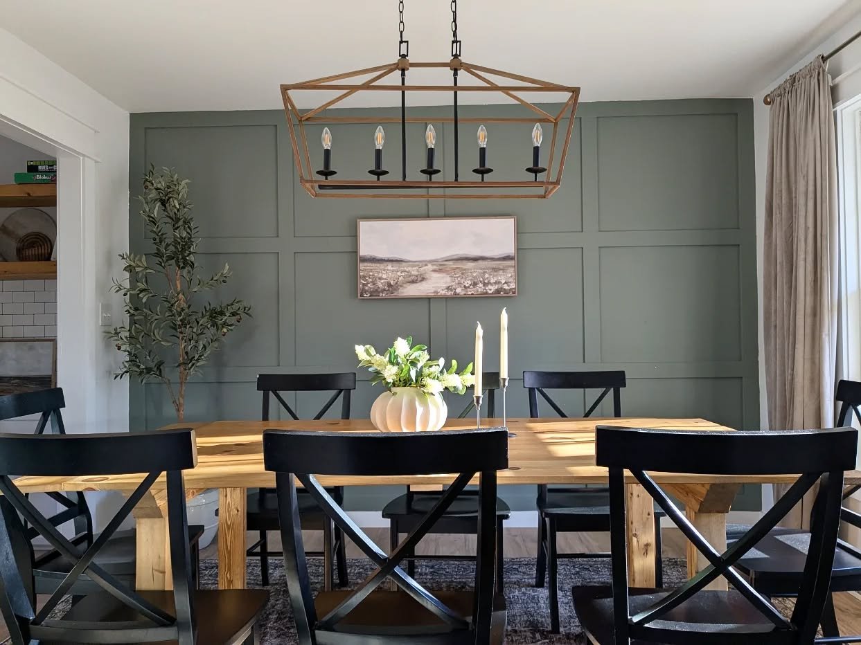 Sage green dining room accent wall featuring square board and batten molding with a wooden farmhouse table.