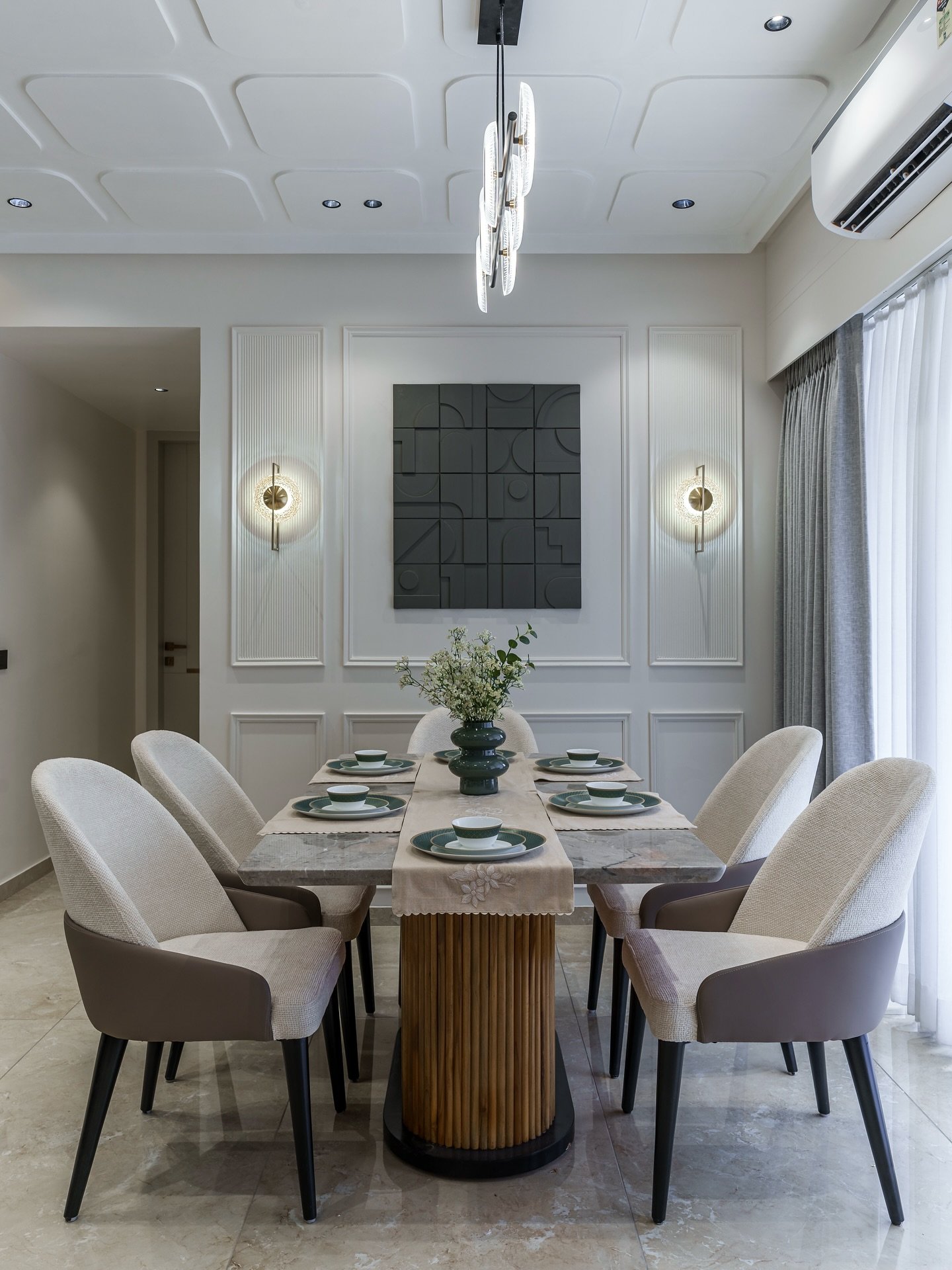 Modern dining room featuring white panel molding, black 3D geometric art, and ring sconces