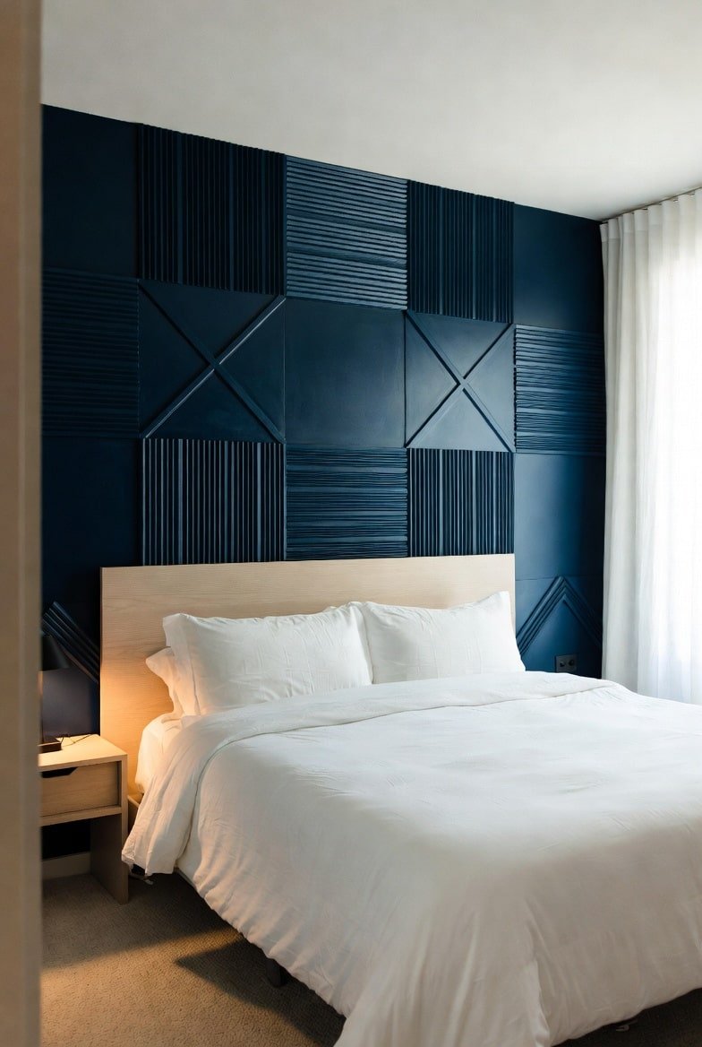 Navy blue 3D geometric panel accent wall with alternating ridged squares behind light wood headboard