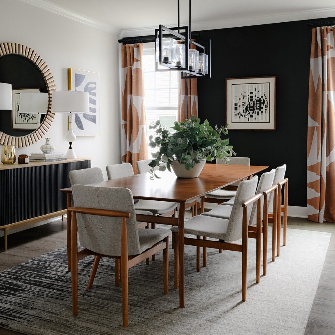 Modern dining room featuring black accent wall with abstract art and patterned curtains