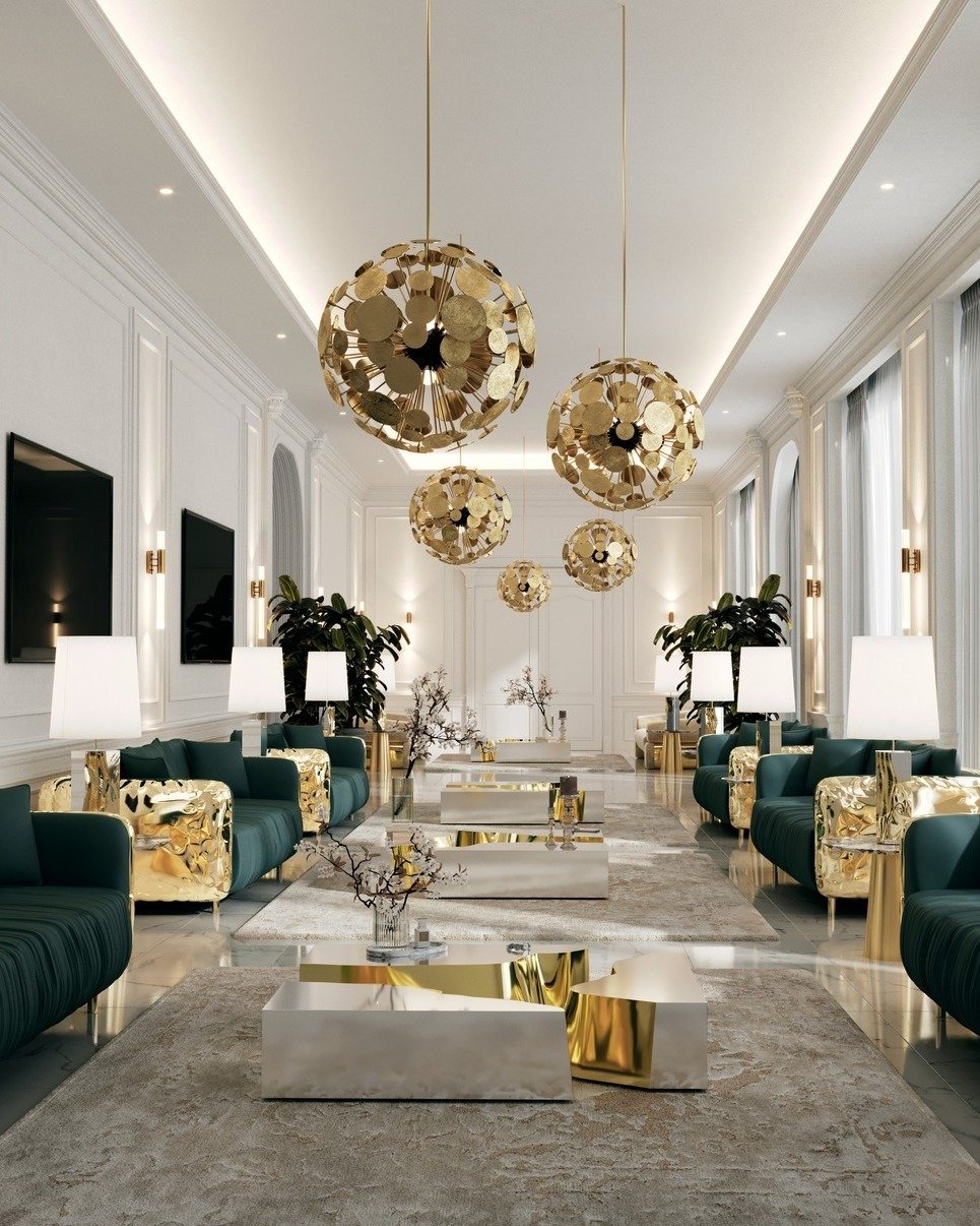Long luxurious living room with multiple large gold sphere pendant lights hanging from the ceiling and wall sconces lining the white panelled walls, leading to a far door.
