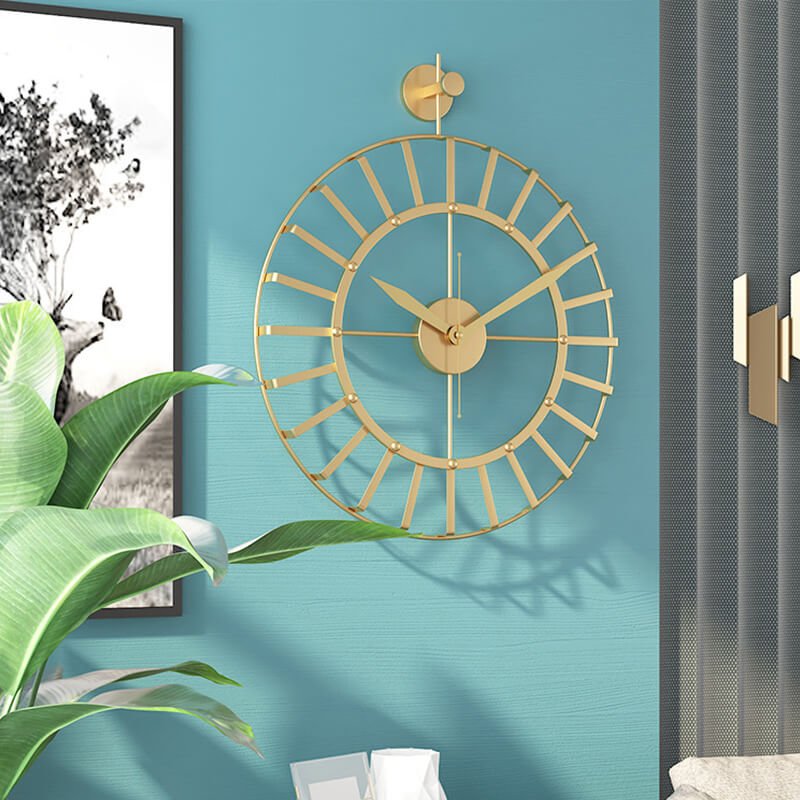 Gold metal skeleton wall clock mounted on a teal blue accent wall next to a grey textured panel