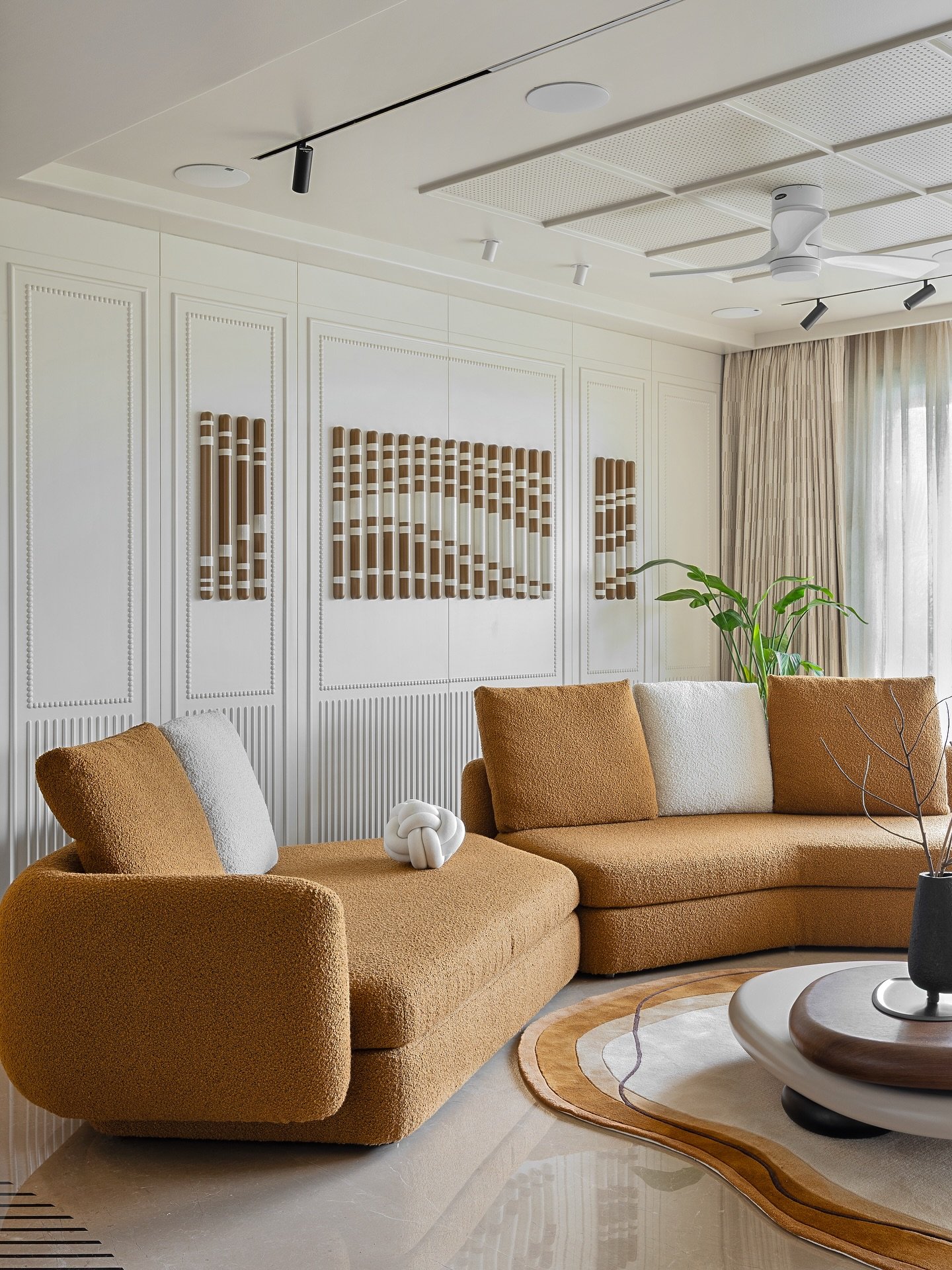 White living room wall with beaded molding, vertical fluting, and 3D brown and white tubular wall art.
