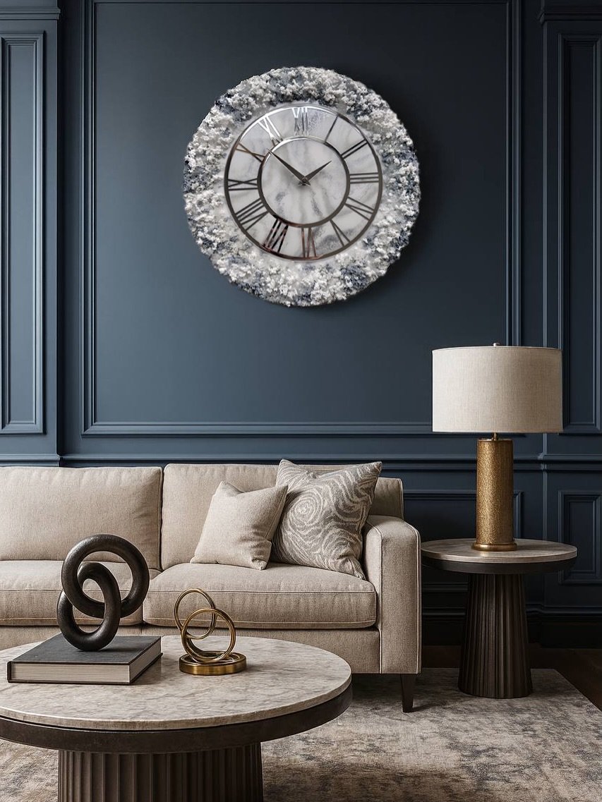 Large resin art wall clock with crystal rim mounted on a dark blue paneled wall above a beige sofa