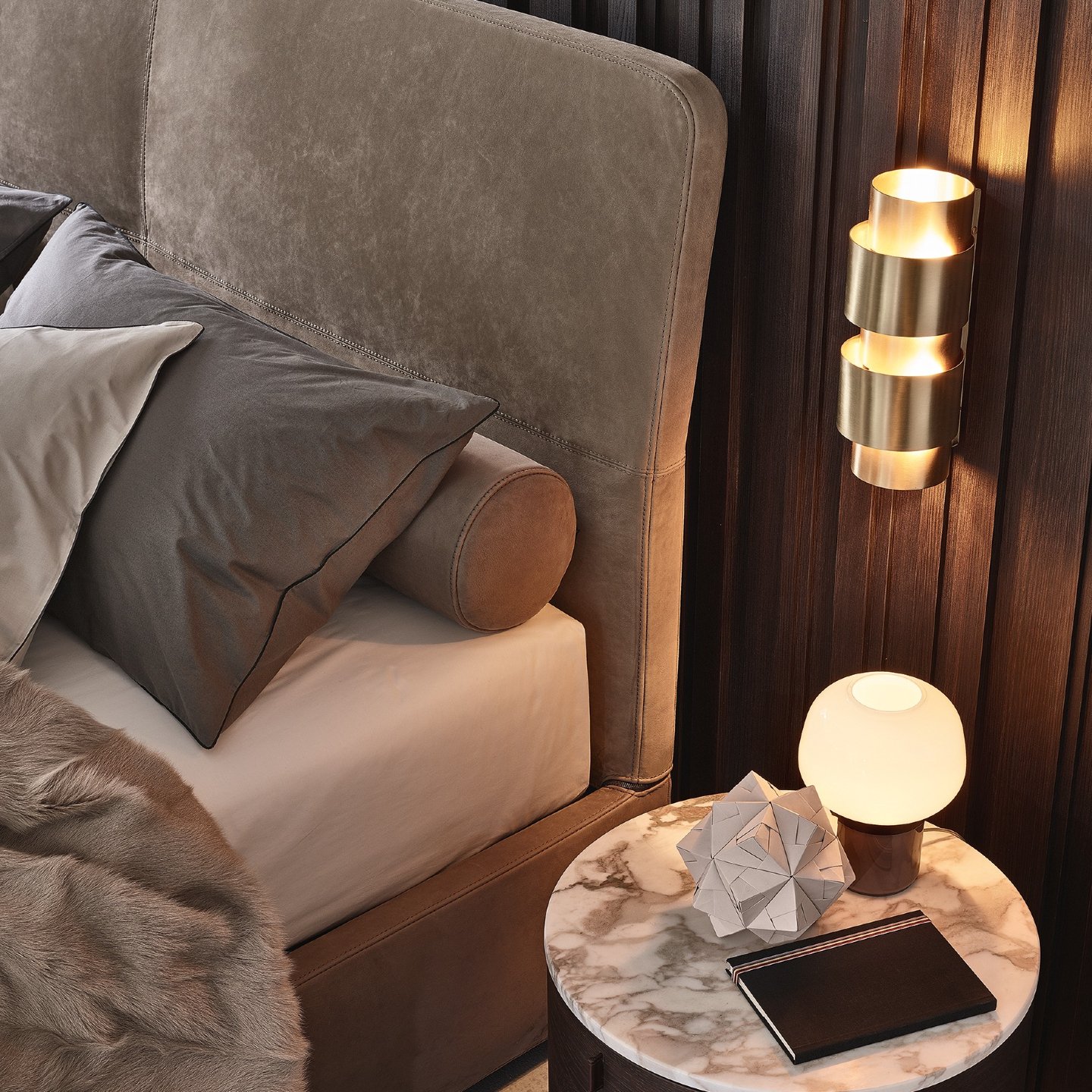 Close-up of dark wood slat bedroom wall featuring a tiered gold sconce and small white table lamp.