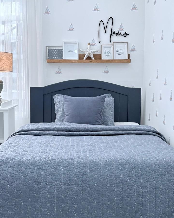 Sailboat wallpaper with wooden shelf and navy headboard