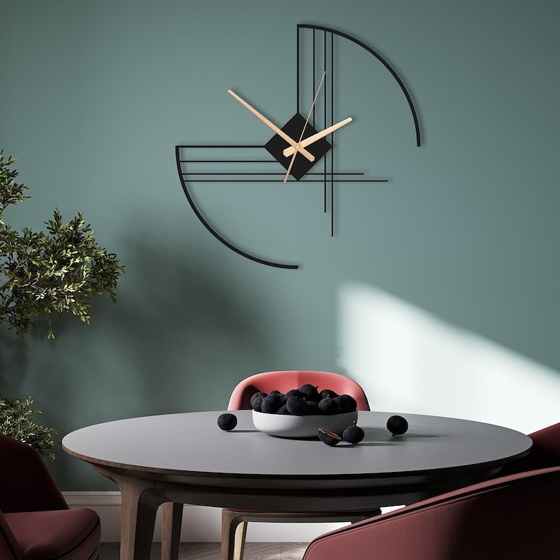 Black abstract geometric wall clock mounted on a teal green dining room wall