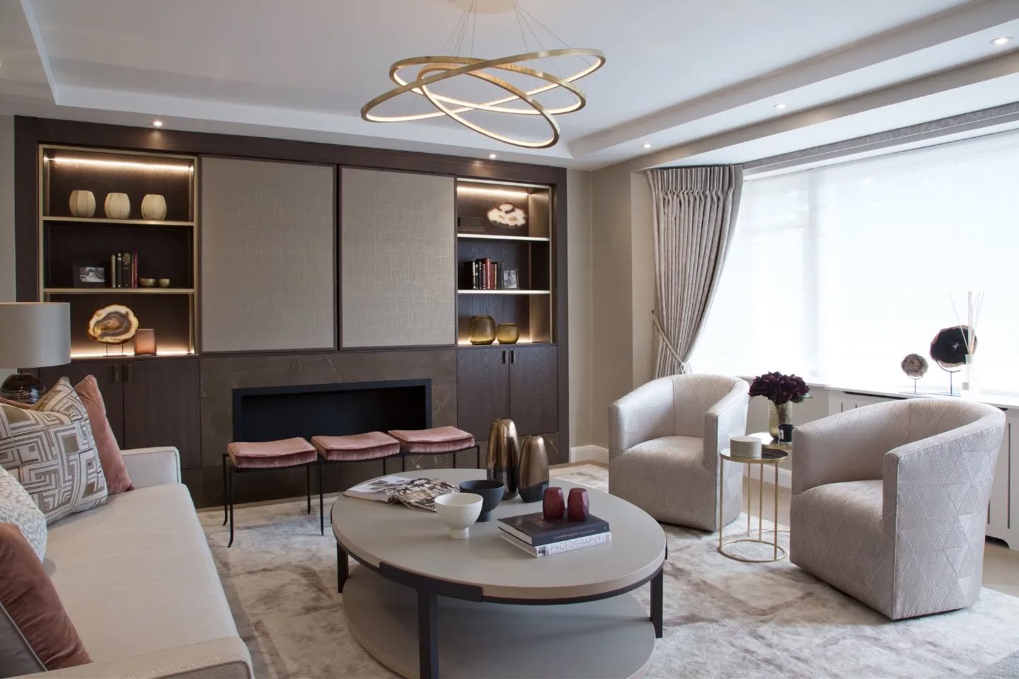 Sophisticated neutral living room featuring a gold interlaced ring chandelier above a round coffee table.