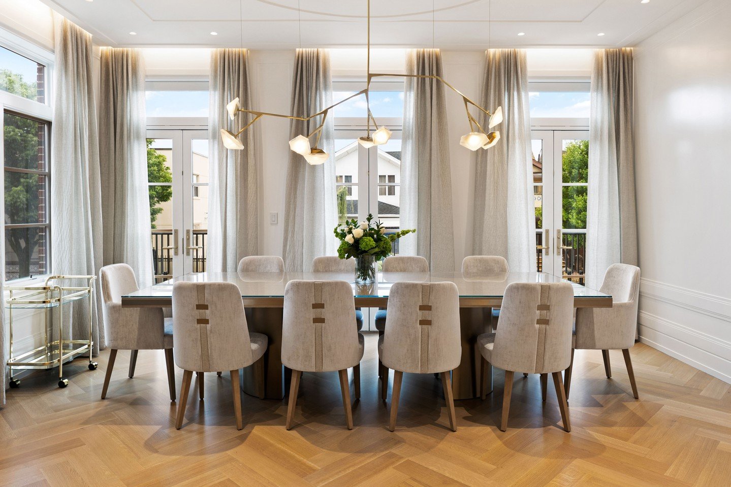 Abstract gold branch chandelier with white geometric shades over glass dining table.