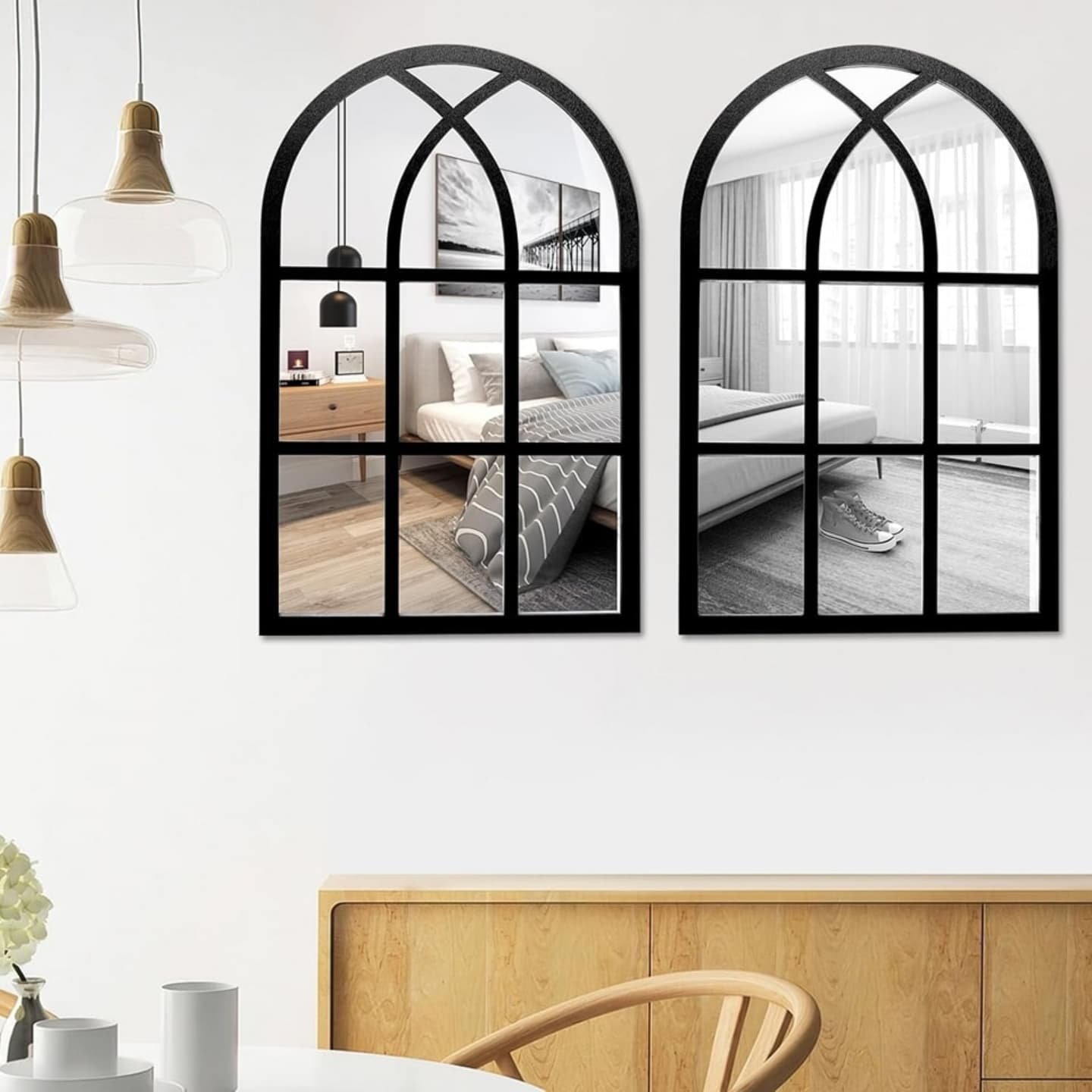 Pair of black arched windowpane mirrors hanging above a wooden sideboard in a dining room.