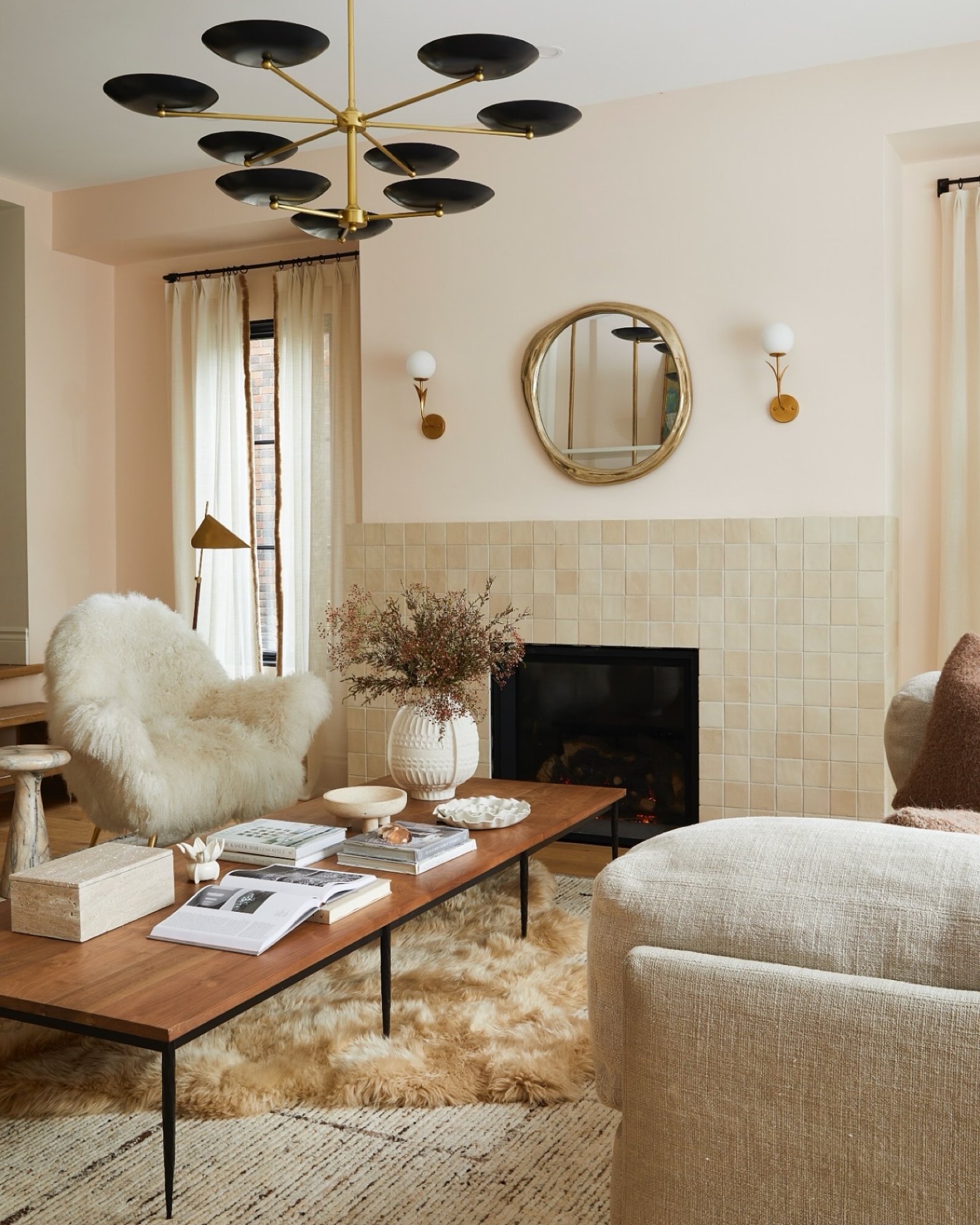 Mid-century modern living room featuring a black and brass multi-arm disc chandelier above a wooden coffee table and tiled fireplace.