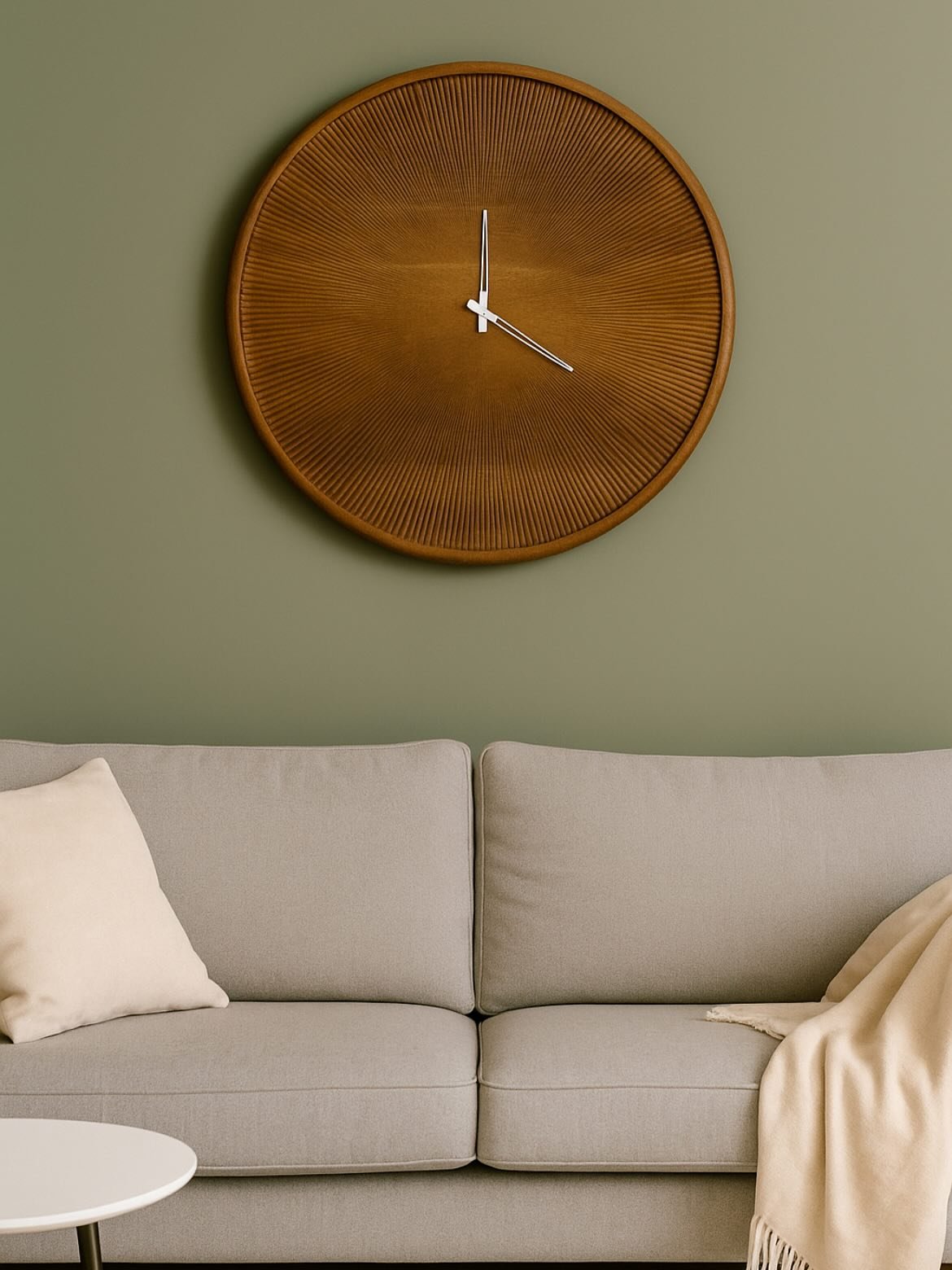 Large round wooden wall clock with ridged texture hanging on a sage green wall above a grey sofa