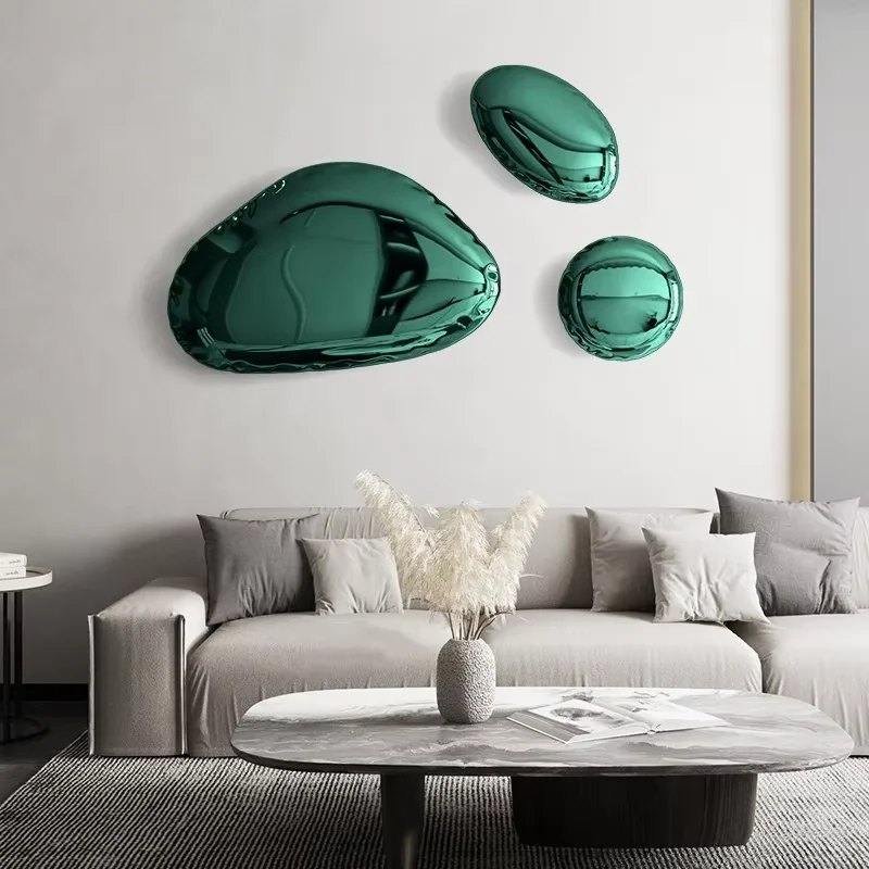 Three emerald green convex organic shaped mirrors mounted above a grey sofa in a modern living room.
