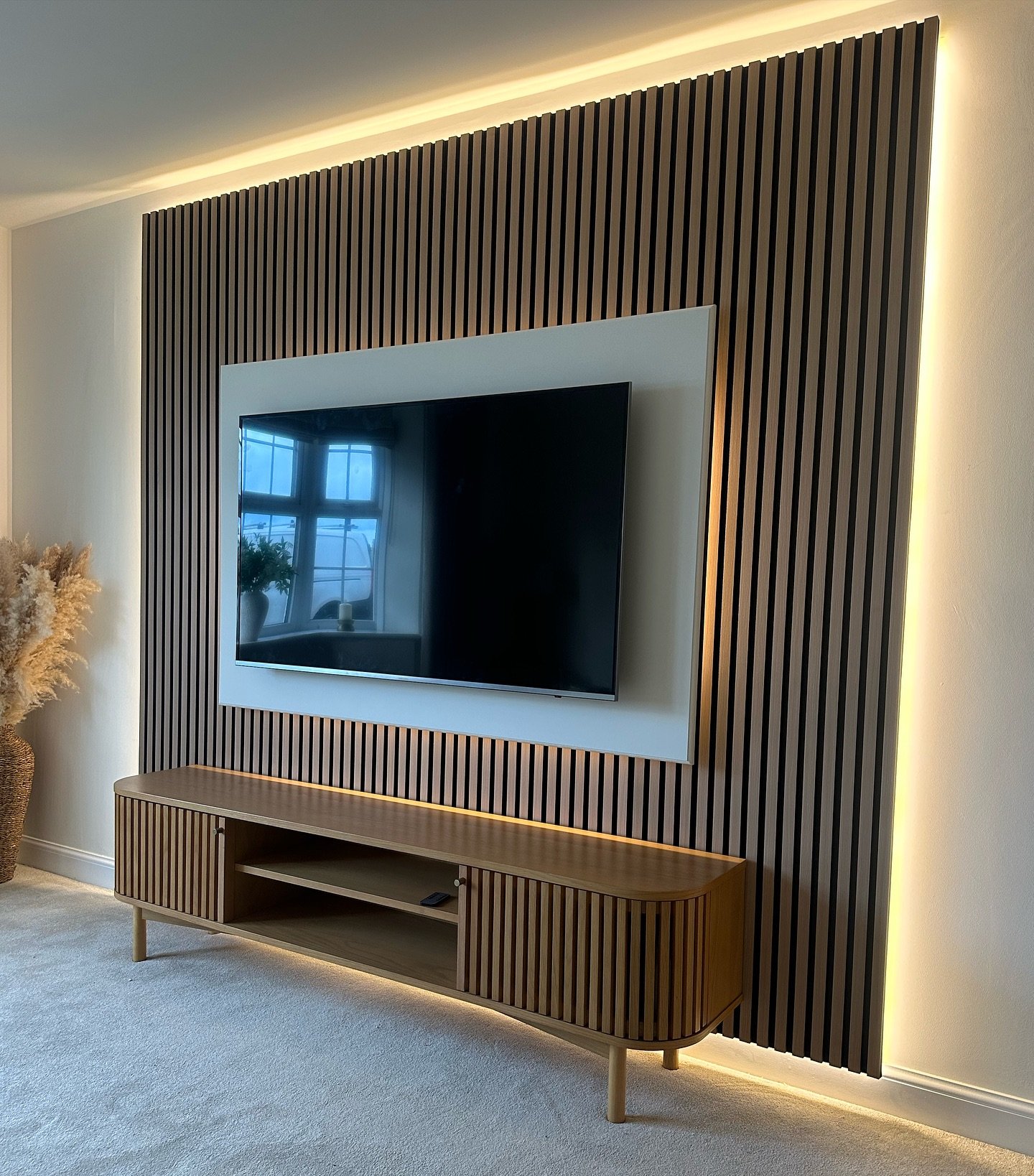 Wood slat accent wall with warm LED backlighting behind the panels and under the media console.