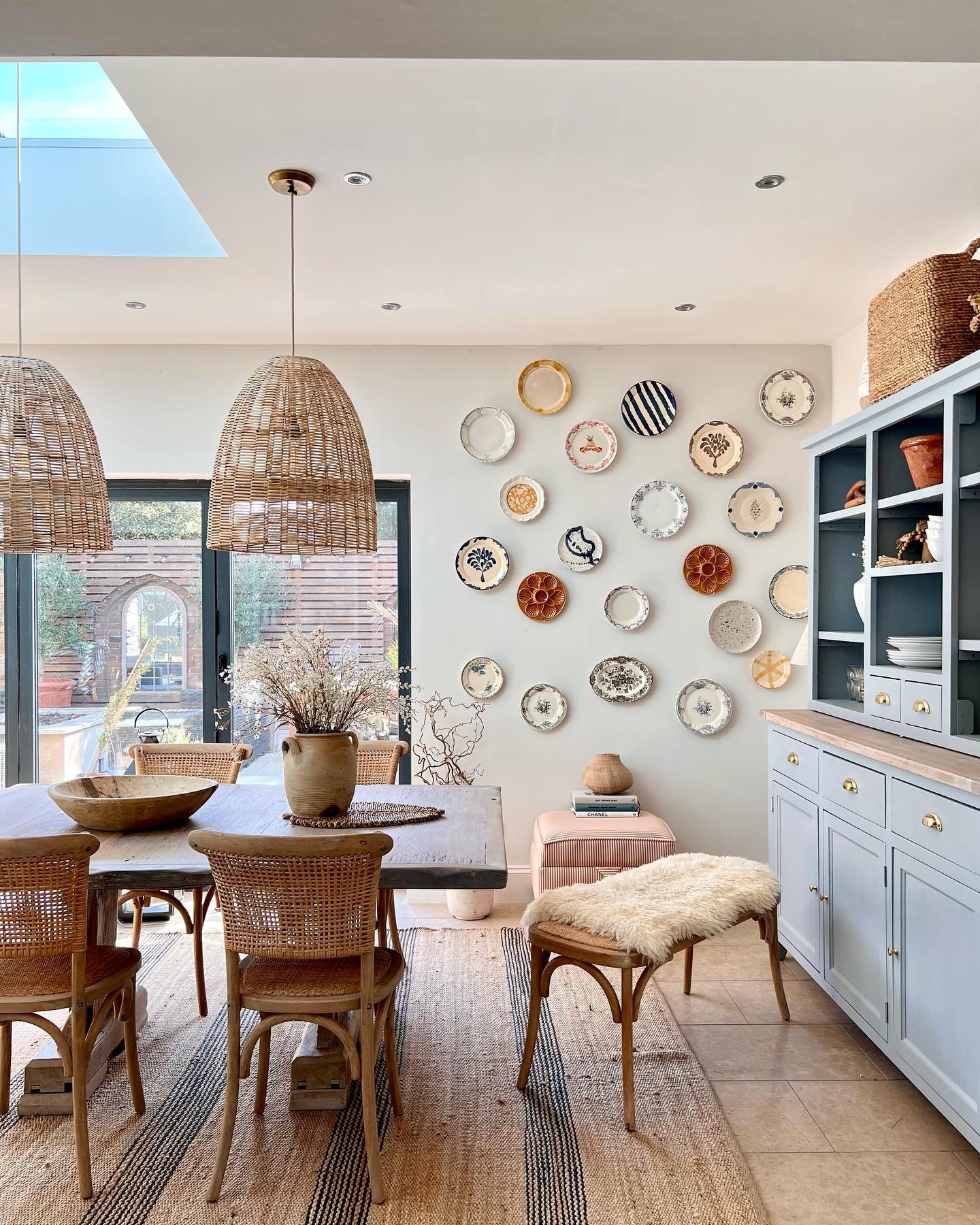Bright dining area featuring a large collection of mismatched patterned plates arranged on a white wall