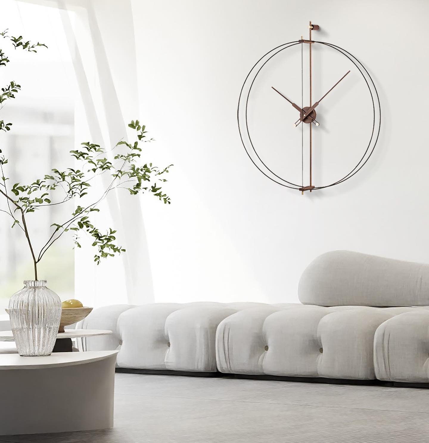 Large double-ring skeleton clock hanging on a white wall above a modern white tufted sofa