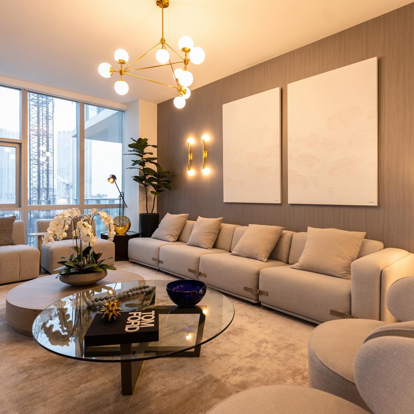 Contemporary living room with a geometric gold branch chandelier and matching wall sconces against a gray textured wall.