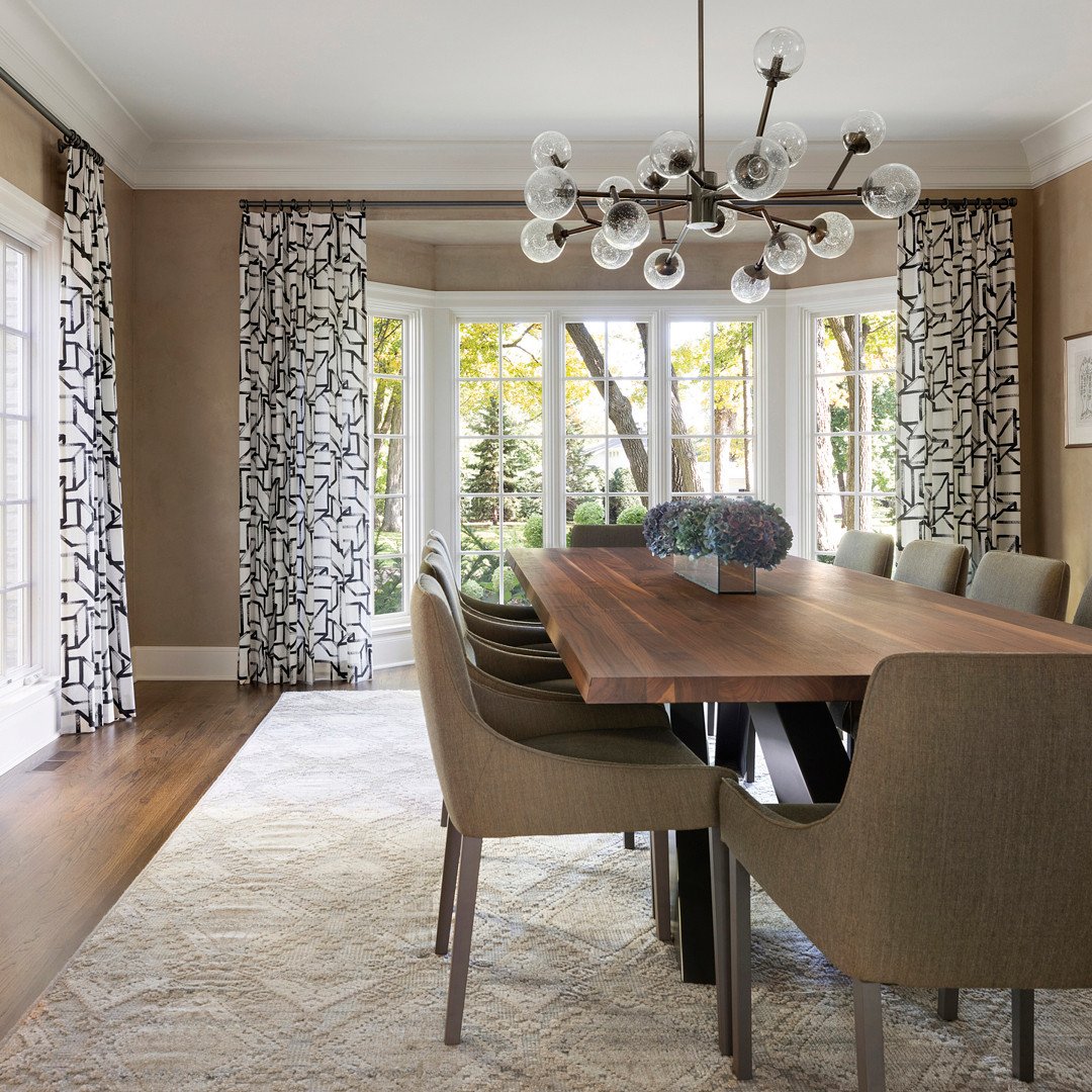 Glass globe sputnik chandelier over wood dining table with patterned curtains.