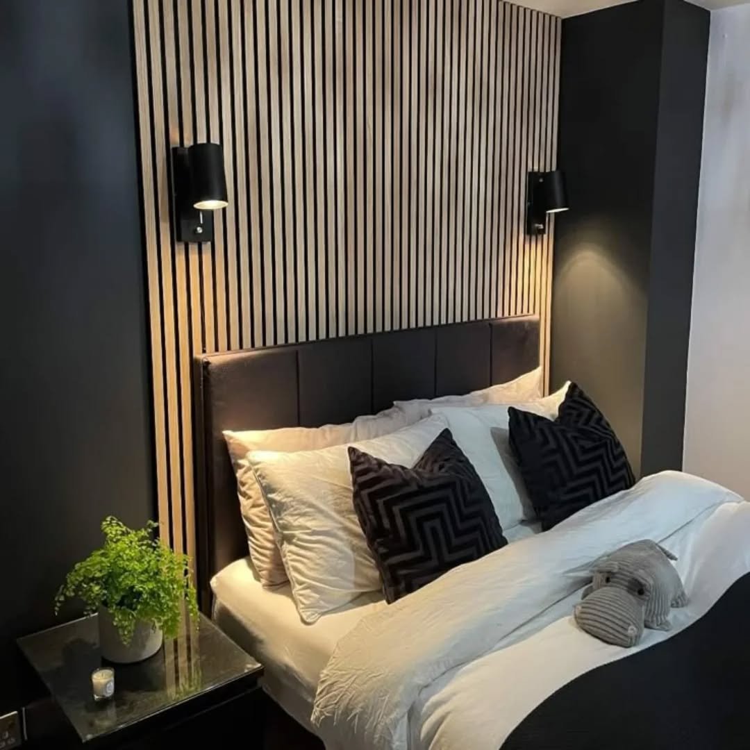 Light wood vertical slat wall paneling with black sconces behind headboard